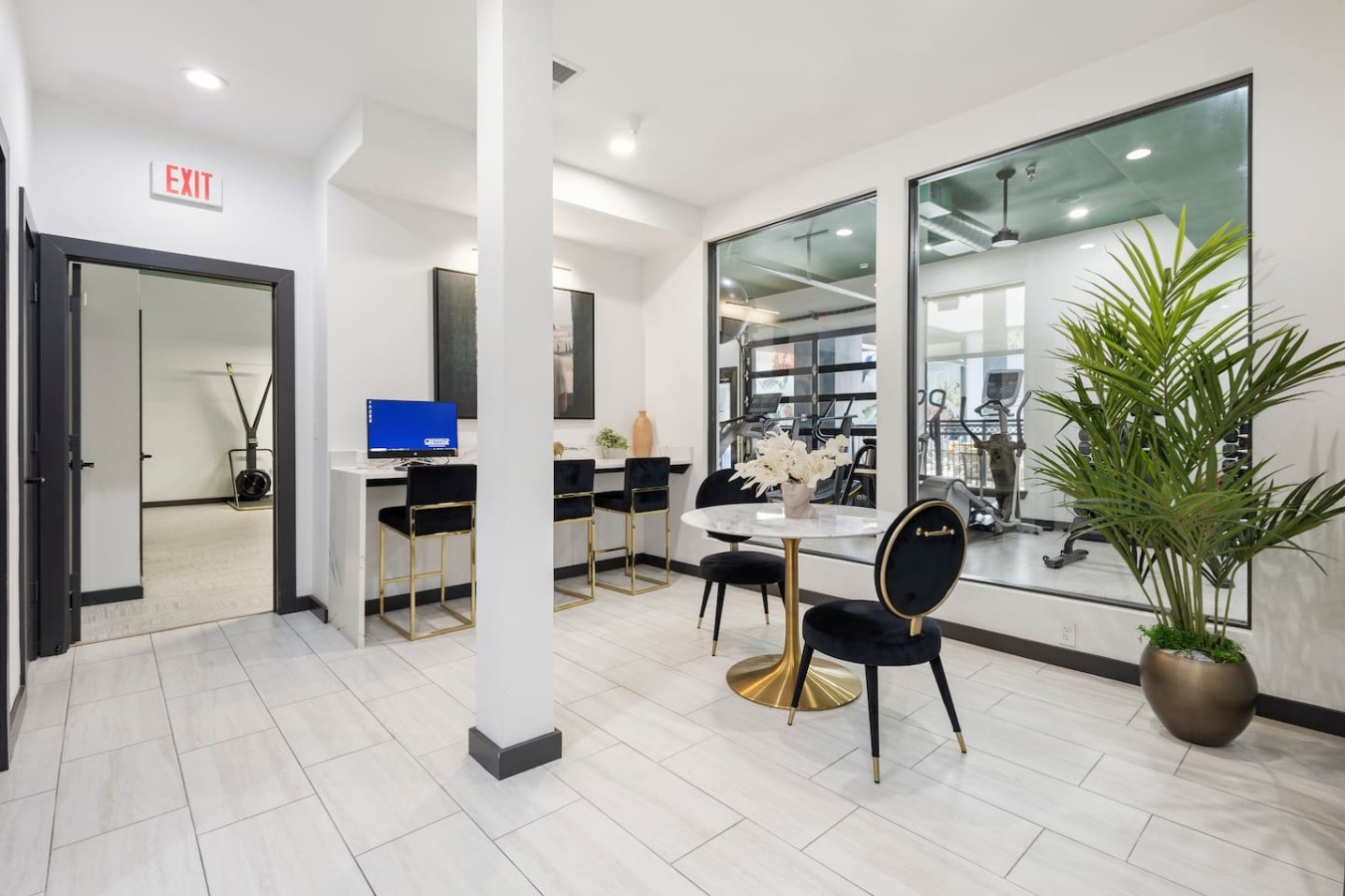 Shared business center adjacent to fitness area with computer and seating for guest use.