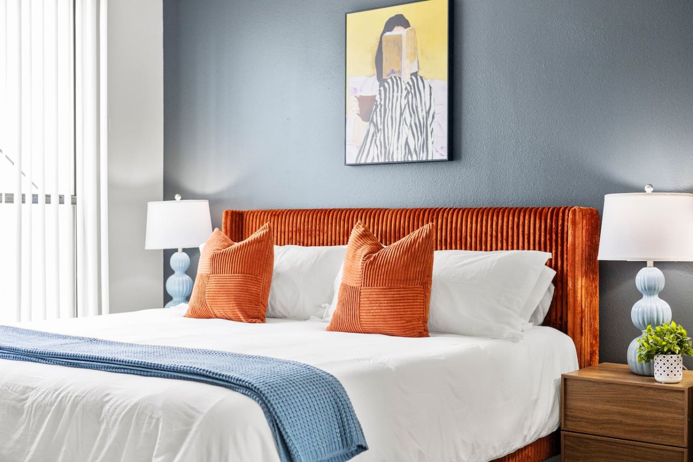 Close-up of king bed with accent pillows and modern decor.