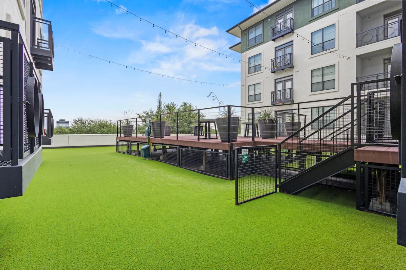 Shared deck with fenced green area and seating, ideal for pets or outdoor relaxation.