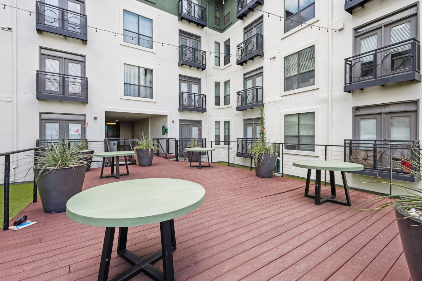 Shared rooftop deck with tables and planters for relaxing or socializing.