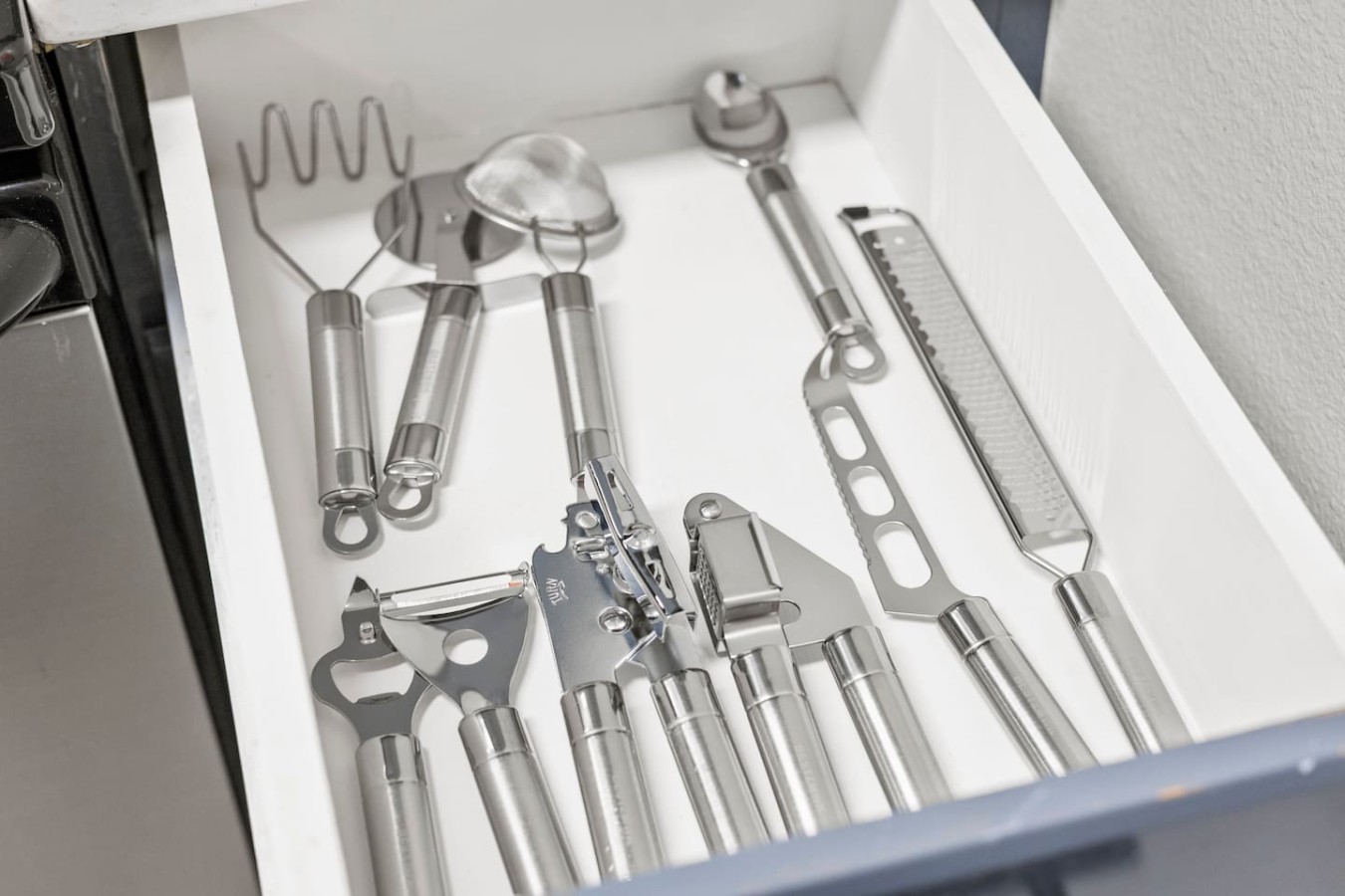 Drawer stocked with utensils and kitchen tools for cooking convenience.
