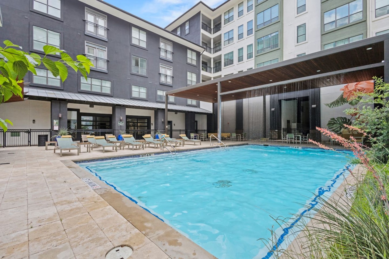 Shared pool courtyard with lounge chairs and shaded seating.