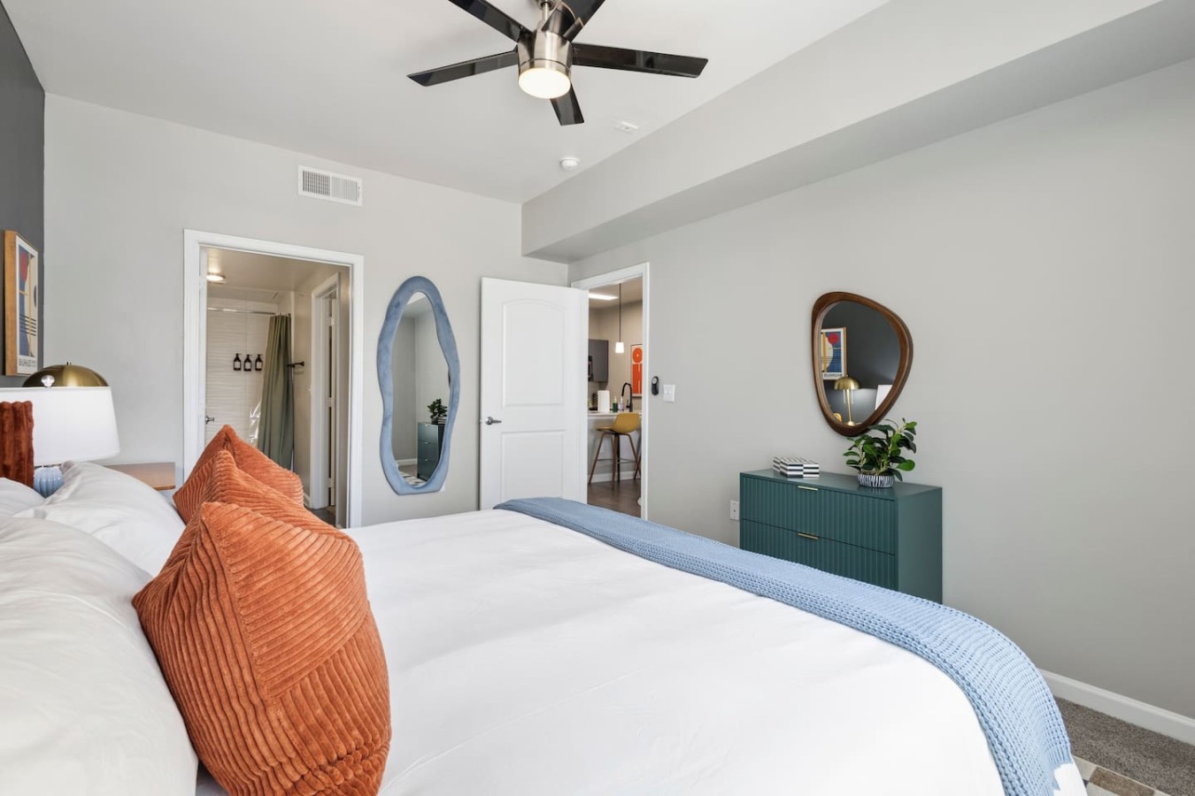 Bright bedroom with king bed, ceiling fan, and open view to living area.