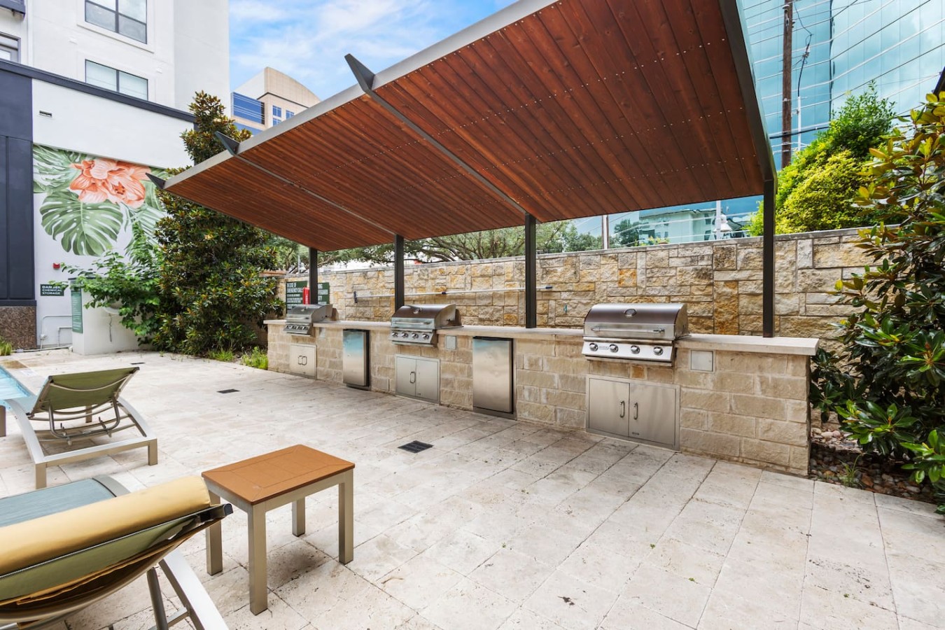 Poolside grilling area with shaded outdoor kitchen and lounge seating.