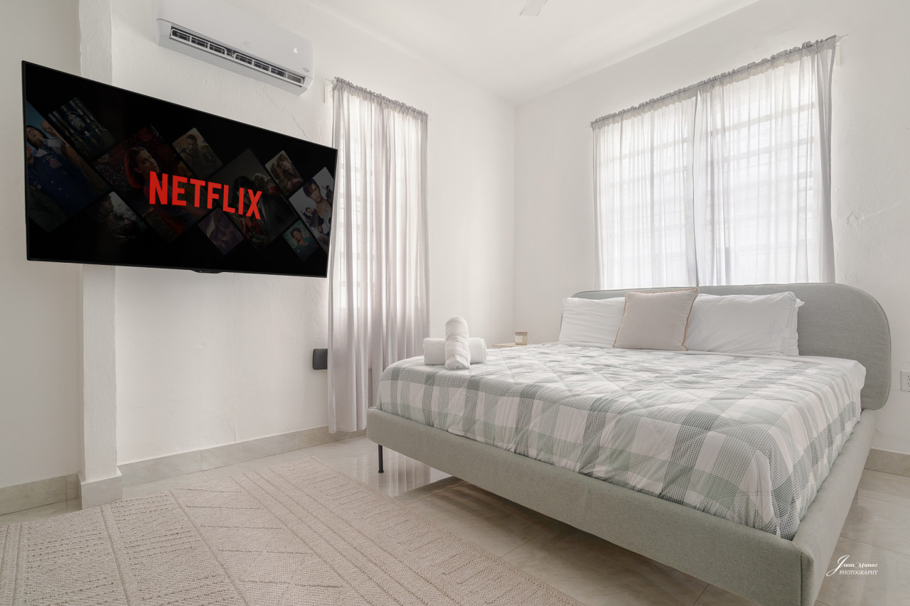 Bedroom with a bed and a flat screen TV mounted on the wall — Villa Blanca | San Juan | La Plácita, Miramar