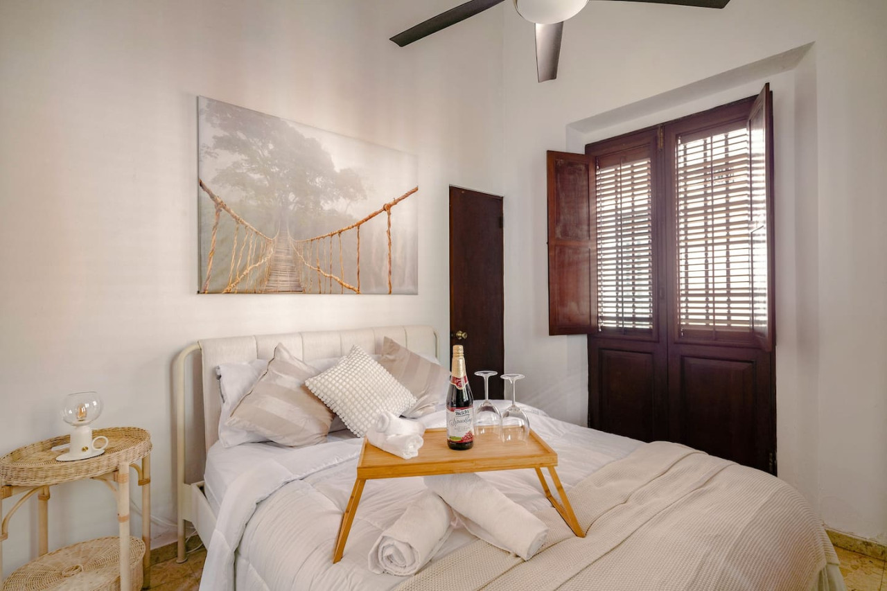 Bedroom with a bed, a table with a bottle of wine and two wine — Ocean Breeze | Old San Juan | Spanish Style, Old San Juan