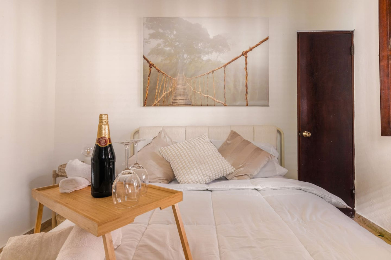 Bedroom with a bed, a painting on the wall, and a bottle of wine — Ocean Breeze | Old San Juan | Spanish Style, Old San Juan
