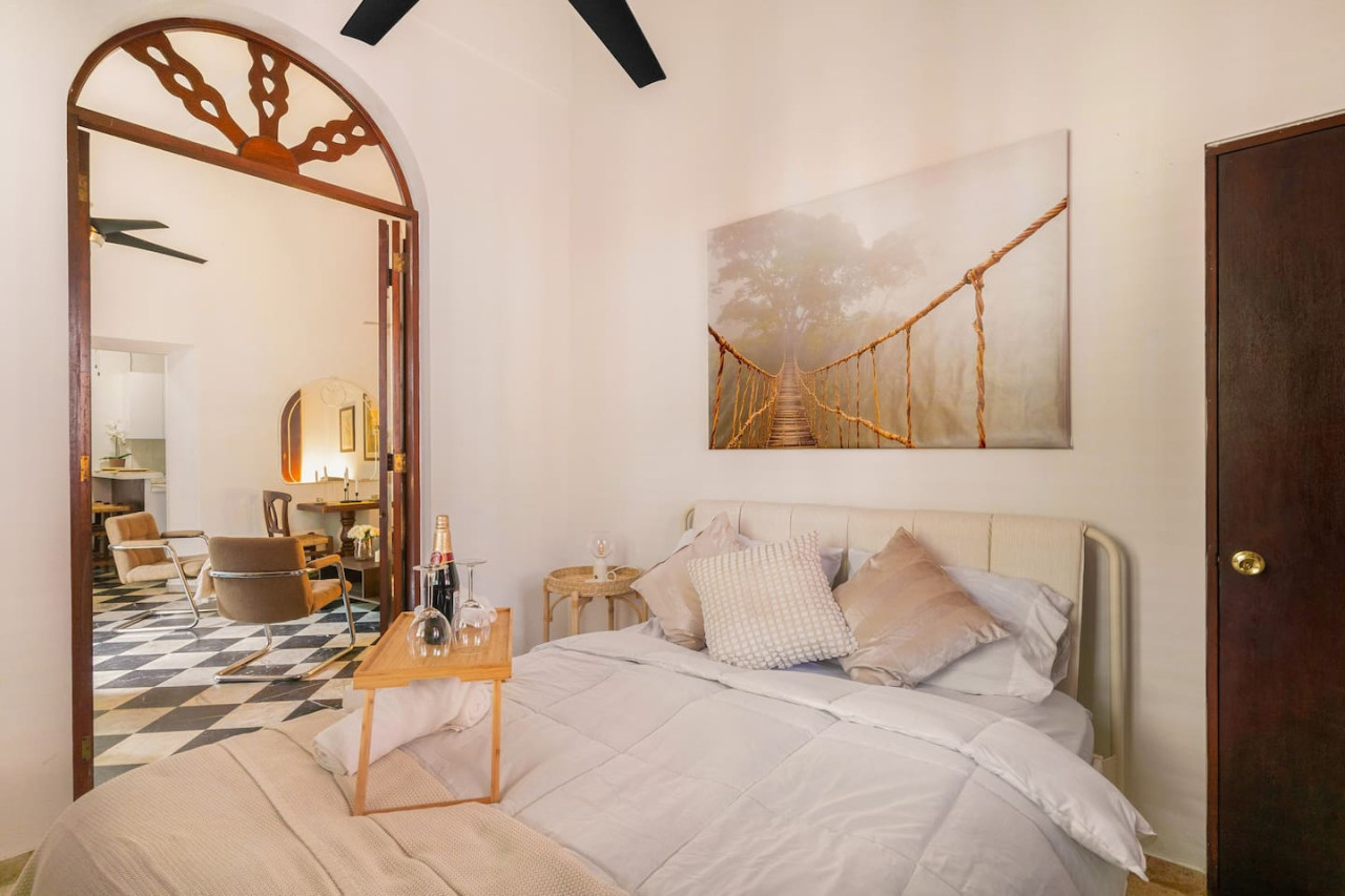 Bedroom with a white bedspread and a painting on the wall — Ocean Breeze | Old San Juan | Spanish Style, Old San Juan