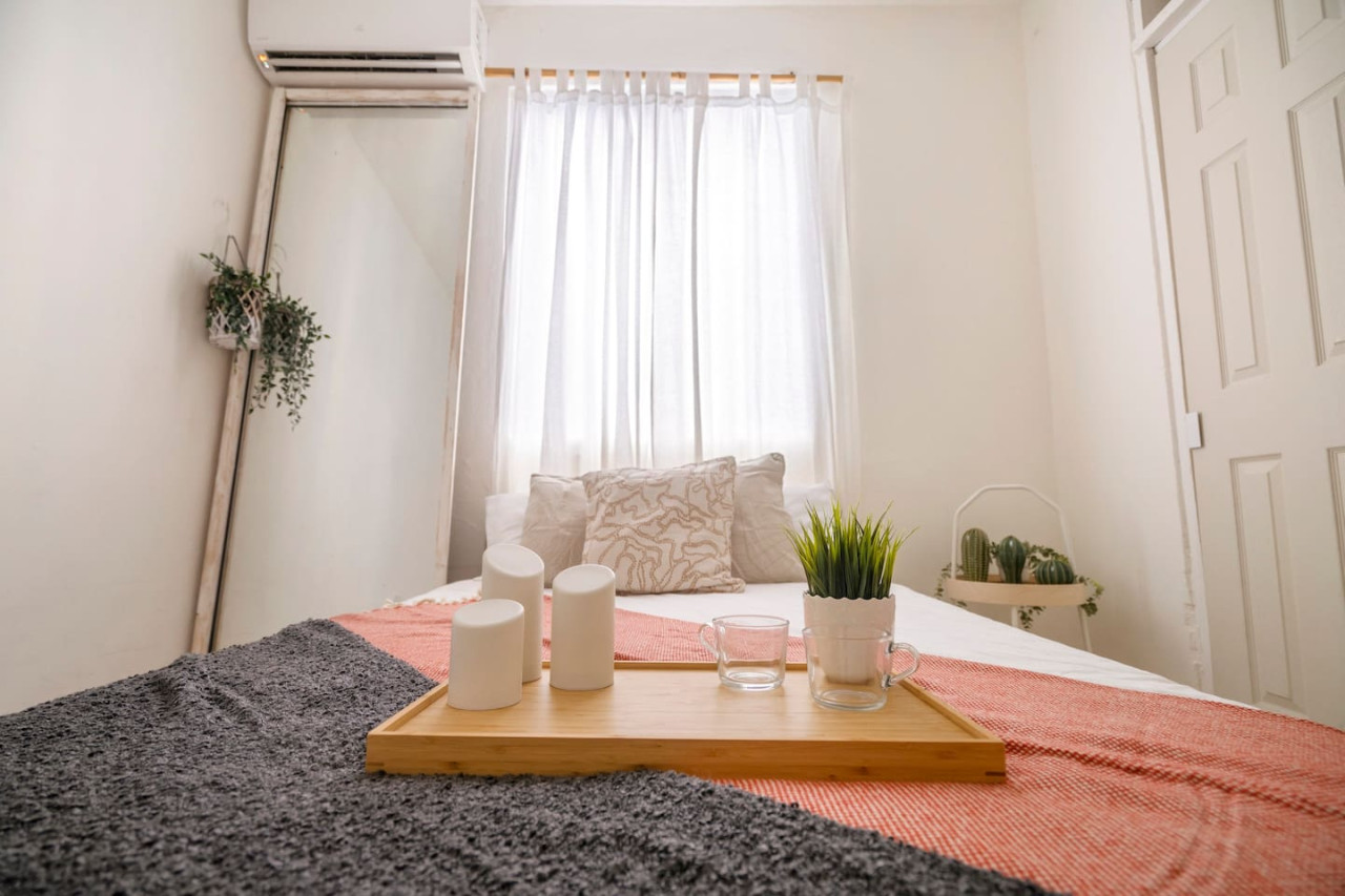 Bedroom with a bed, a table with three white candles, a vase with — Sunset Haven | Ocean Breeze | Old San Juan, Old San Juan