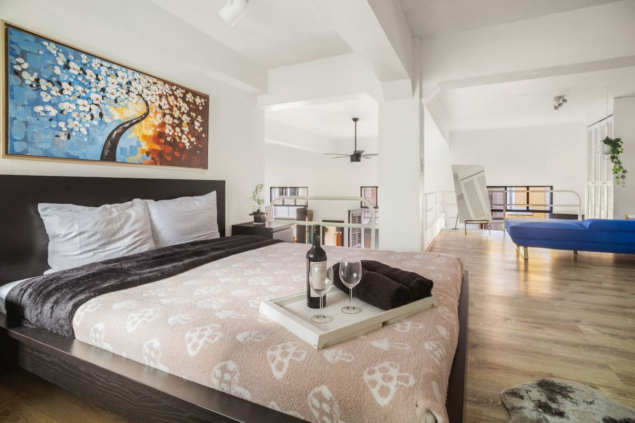 Bedroom with a bed, a table with a bottle of wine and a wine — Spanish Duplex | Private Patio | Walk to Ocean, Old San Juan