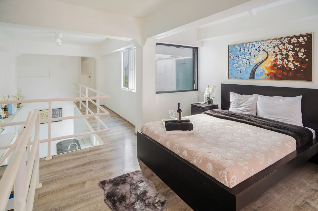 Bedroom with a black bed and a bottle of wine on the — Spanish Duplex | Private Patio | Walk to Ocean, Old San Juan