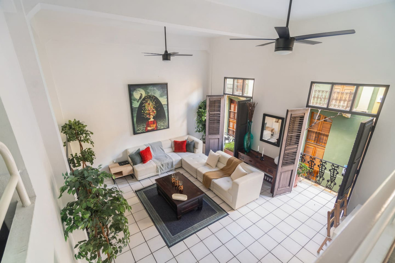 Living room with a couch, coffee table, and potted plants — Spanish Duplex | Private Patio | Walk to Ocean, Old San Juan