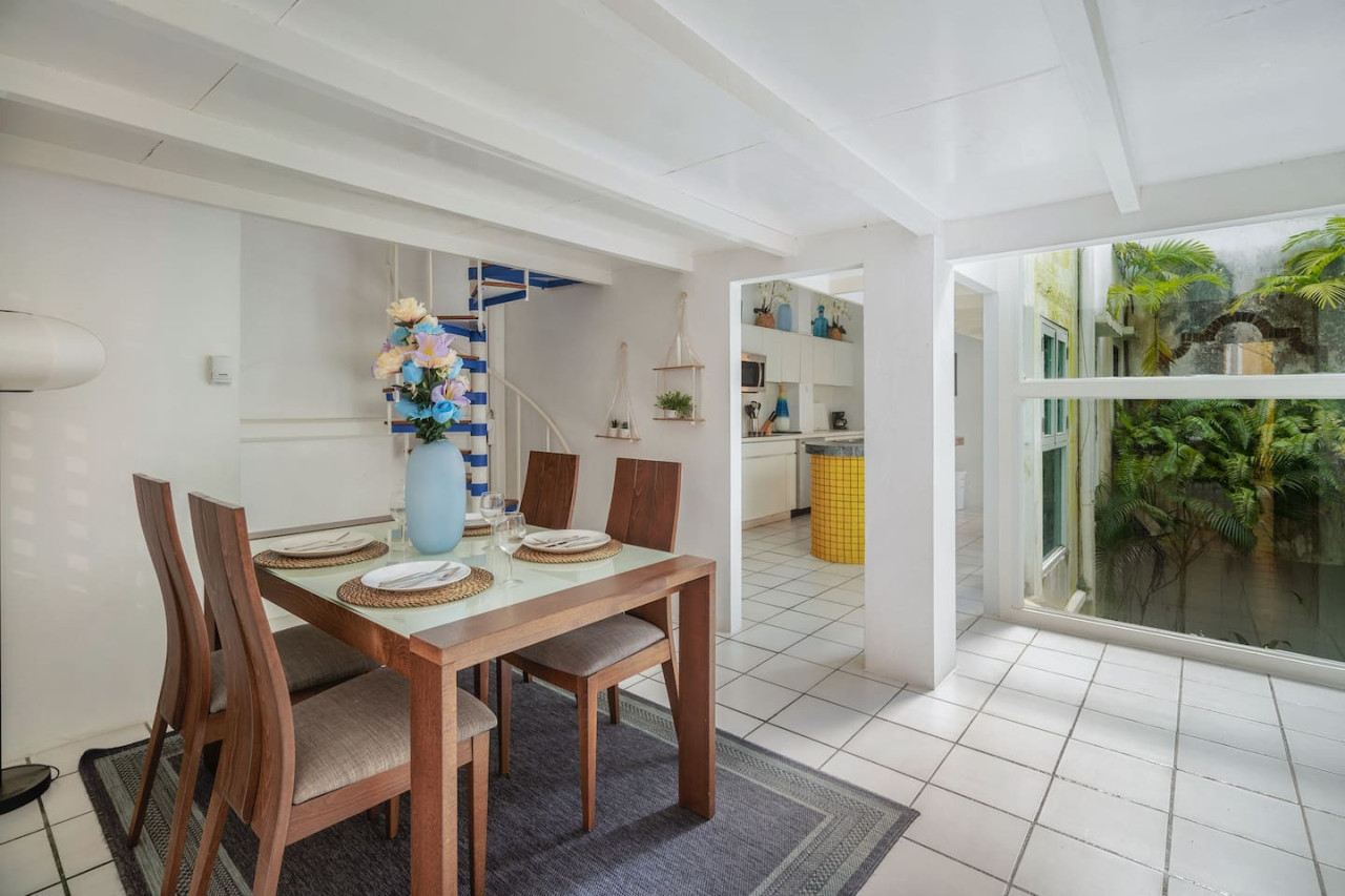 Dining room table with chairs and a vase of flowers on it — Spanish Duplex | Private Patio | Walk to Ocean, Old San Juan