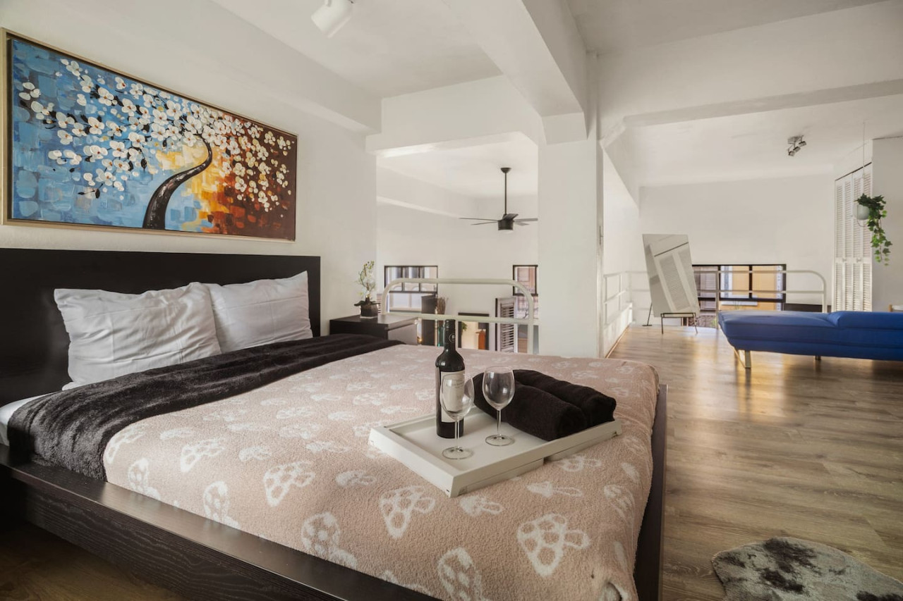 Bedroom with a bed, a bottle of wine, and a vase with flowers — Spanish Duplex | Private Patio | Walk to Ocean, Old San Juan
