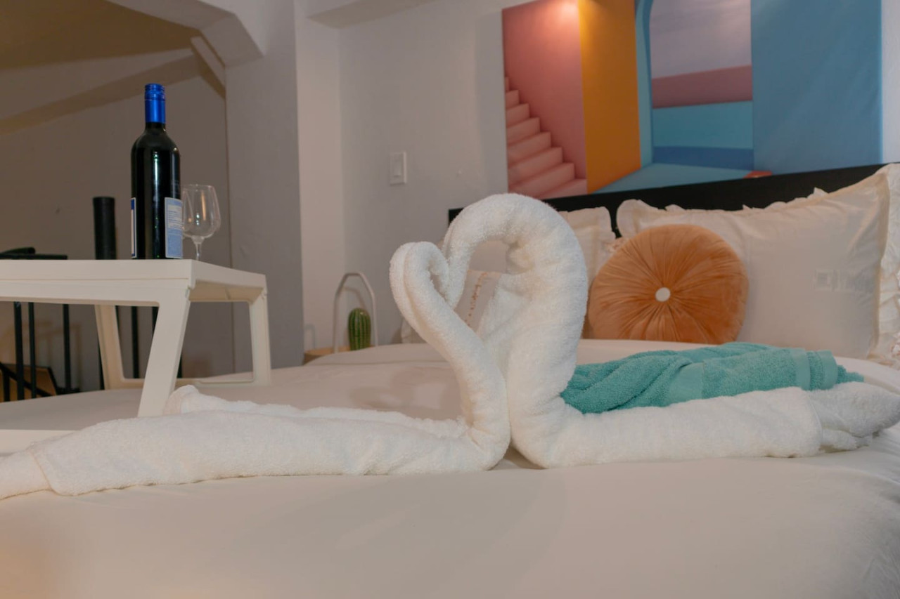 Bedroom with a white bedspread and a heart-shaped towel — Puerto Escape | Old San Juan, Old San Juan