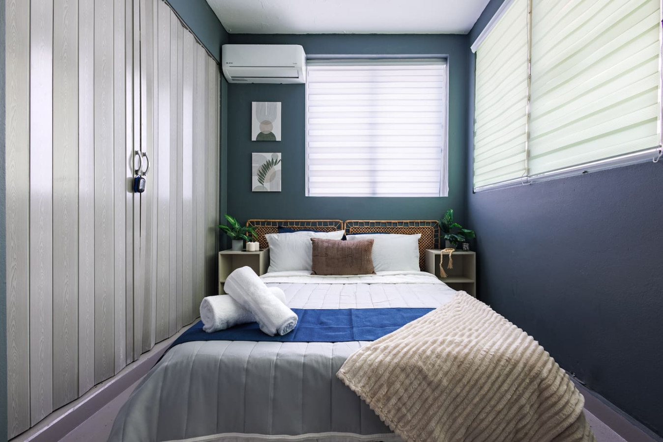Bedroom with a blue bedspread and white towels — Spain Lagoon | San Juan | Private Patio, Santurce