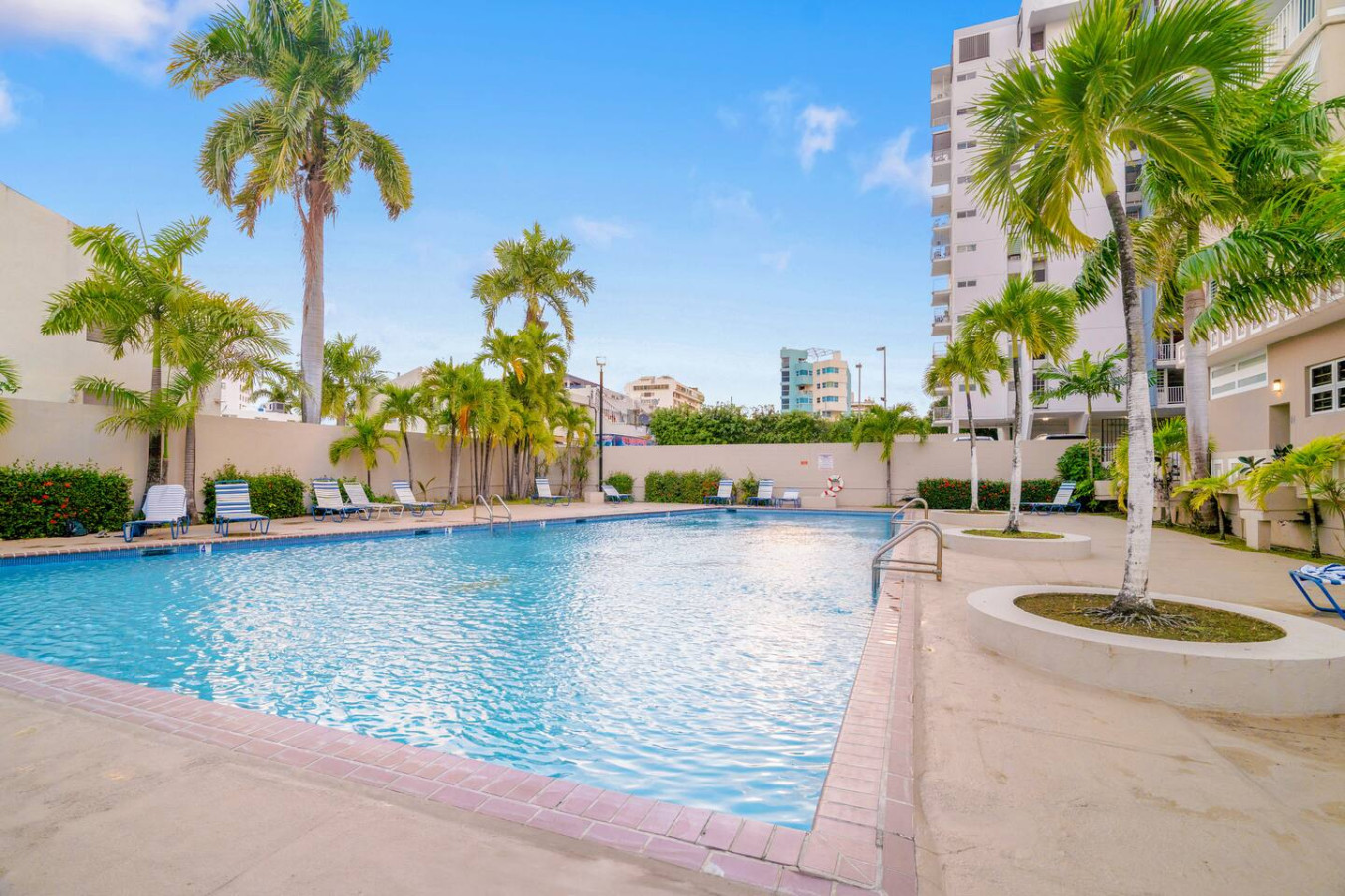 Pool area with palm trees and blue water — OceanSide - Pool Balcony, Isla Verde