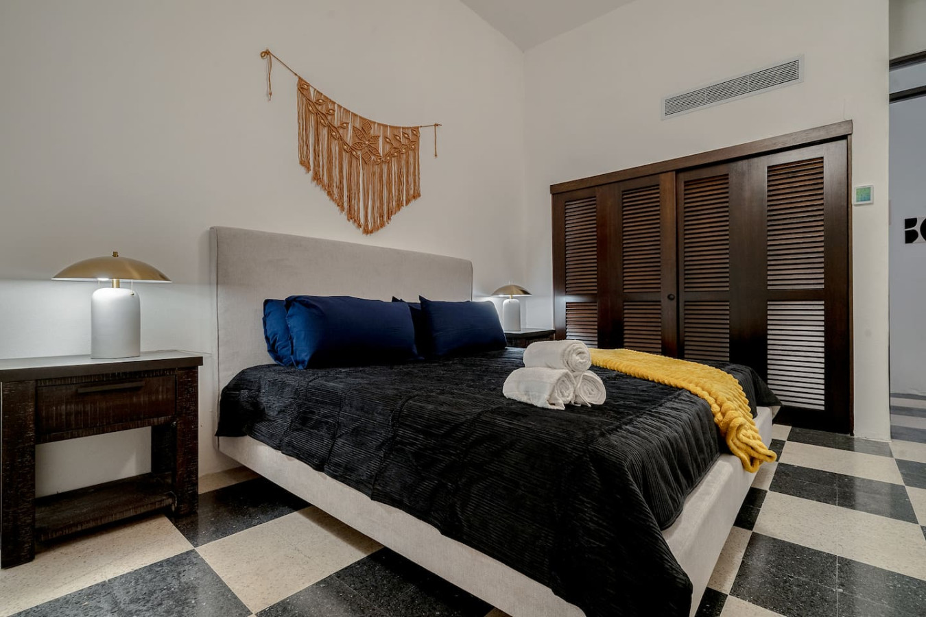 Bedroom with a black bedspread and a yellow blanket on top of it — Royal Palm Old San Juan, Old San Juan