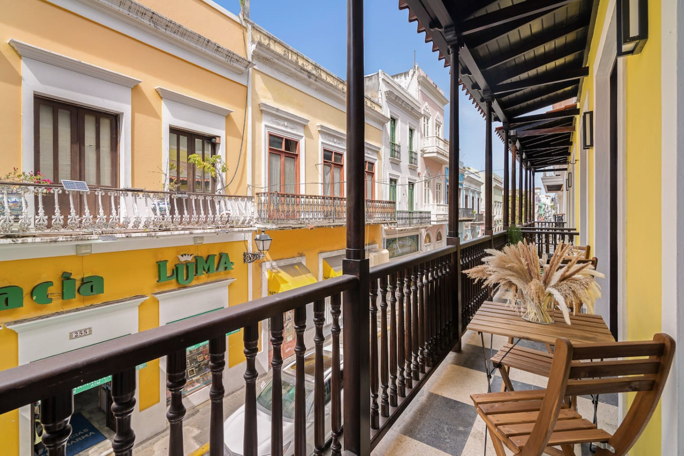 Balcony overlooking a busy street with a yellow building in the background — Soho House  The Grand Patio, Old San Juan