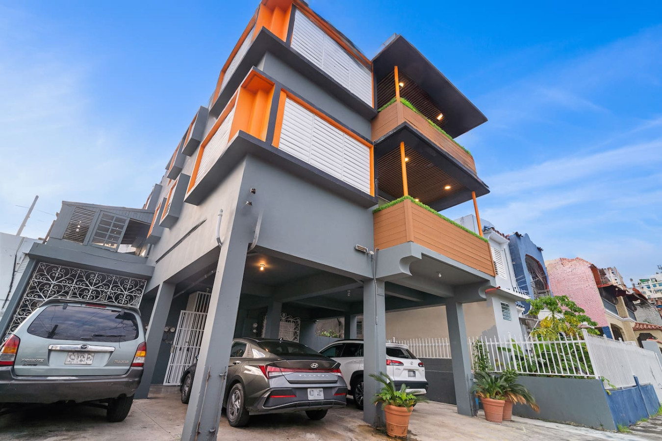 Gray building with orange trim and a carport — Puerto House - Private Patio, Santurce