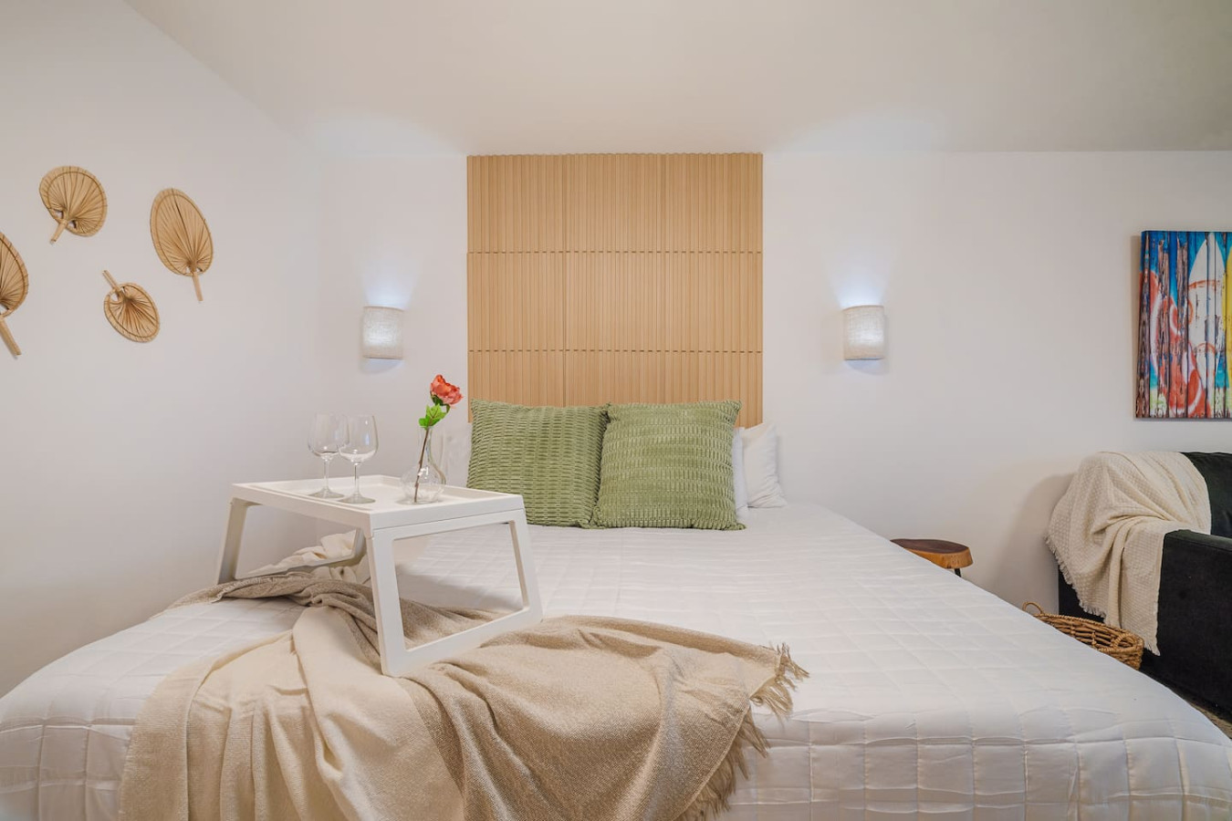 Bedroom with a white bed, a table with two wine glasses, and a vase with a red flower — Condado Penthouse, Condado