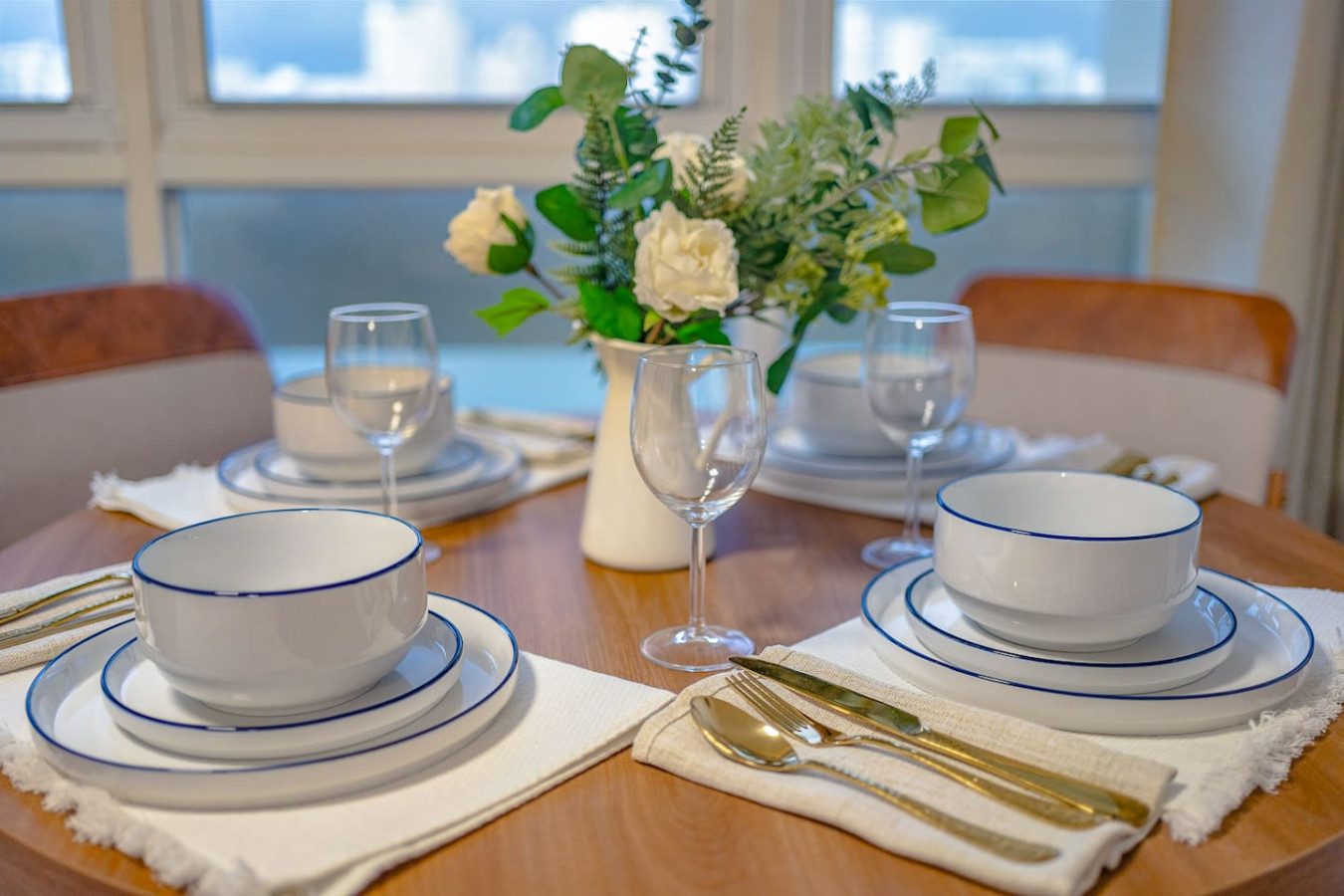 Table set for dinner with white bowls, wine glasses, and a vase of flowers — Condado Penthouse, Condado