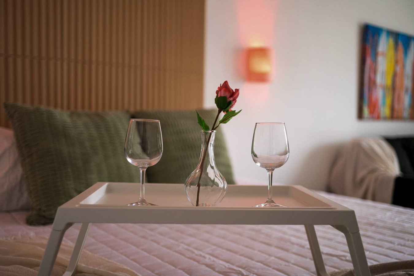 Bedroom with a bed, a table with two wine glasses and a vase with a rose on it — Condado Penthouse, Condado
