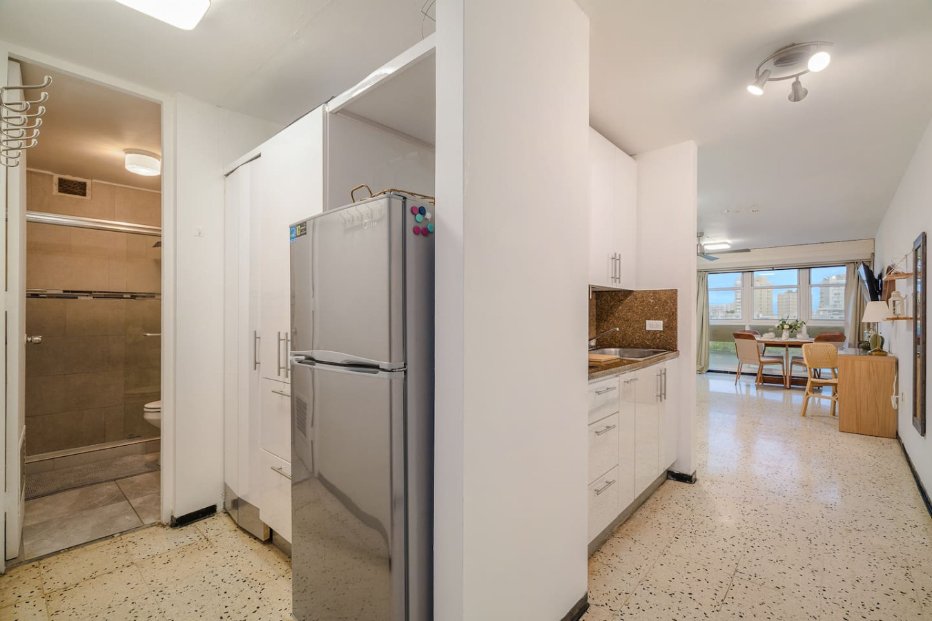 Entry hall with a steel fridge and the main room beyond — Condado Penthouse
