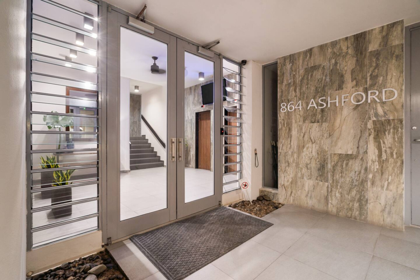 Building's glass front doors and lobby stairs — Condado Penthouse