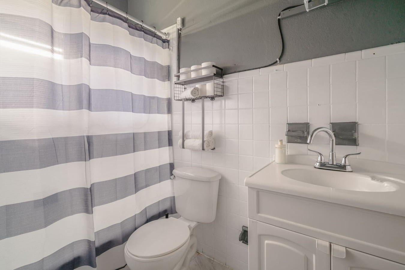 Bathroom with a striped shower curtain and a vanity — Puerto Lagoon Downtown, Santurce