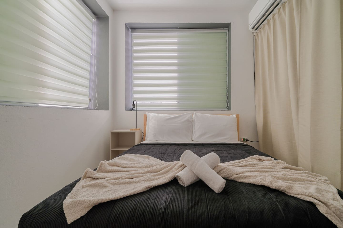 Bedroom with a black bedspread and white towels — Puerto Lagoon Downtown, Santurce