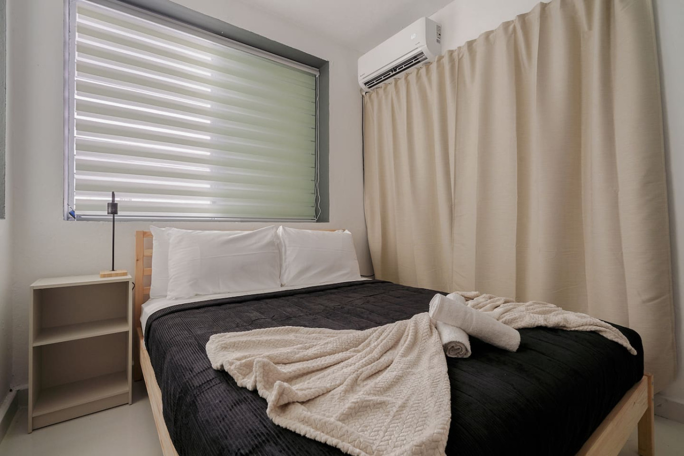 Bedroom with a black bedspread and white sheets — Puerto Lagoon Downtown, Santurce