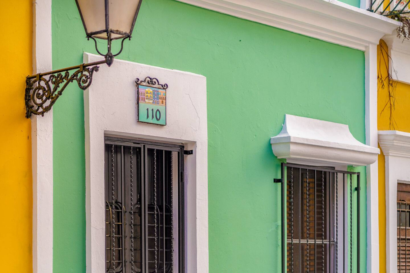 Green facade with a wall lantern and barred windows — Villa Mansion - Fountain & Rooftop - Old San Juan