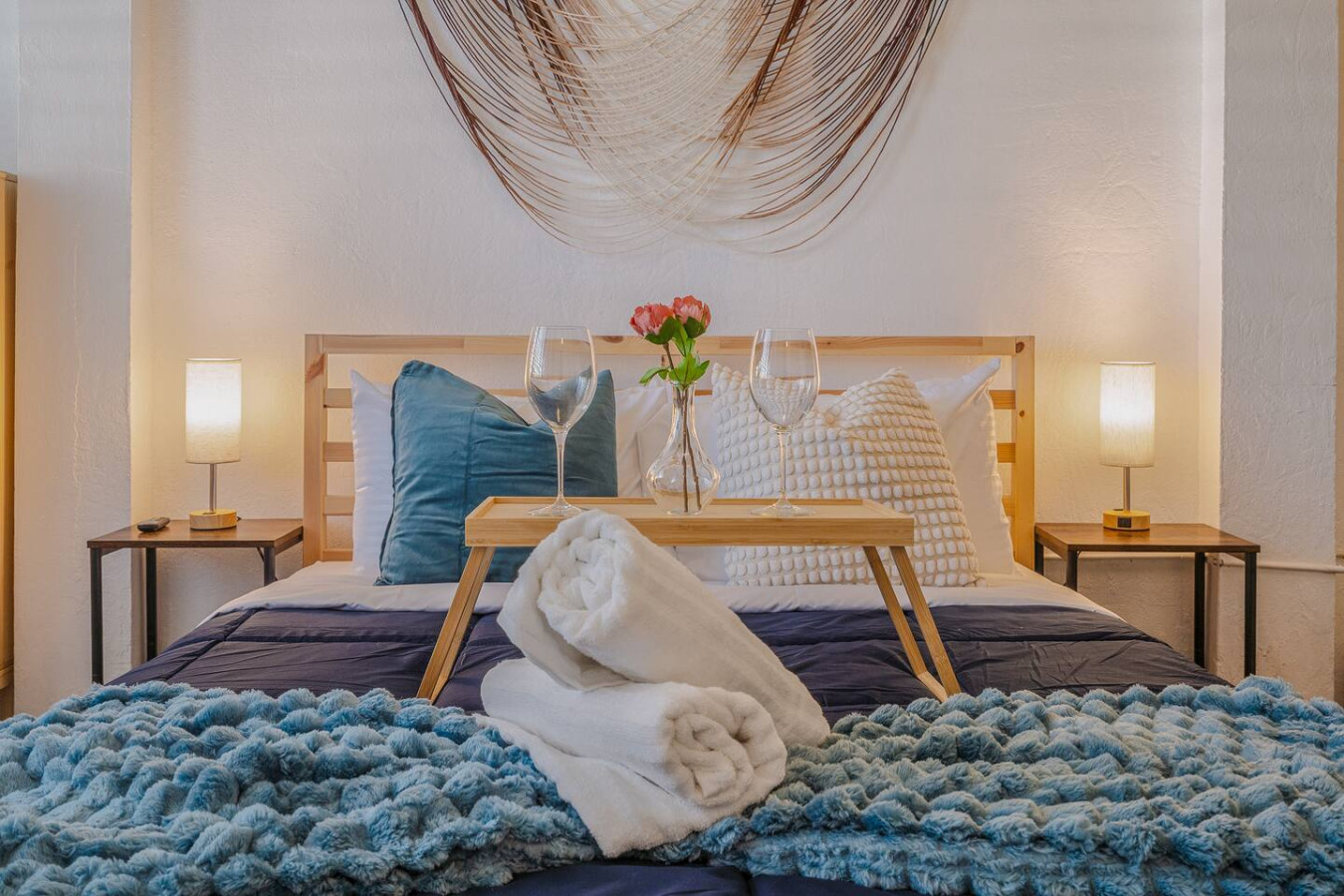 Bedroom with a bed, a table with two wine glasses, and a vase with a flower in — Tapia Mosaic Beachwalk - San Juan, Santurce