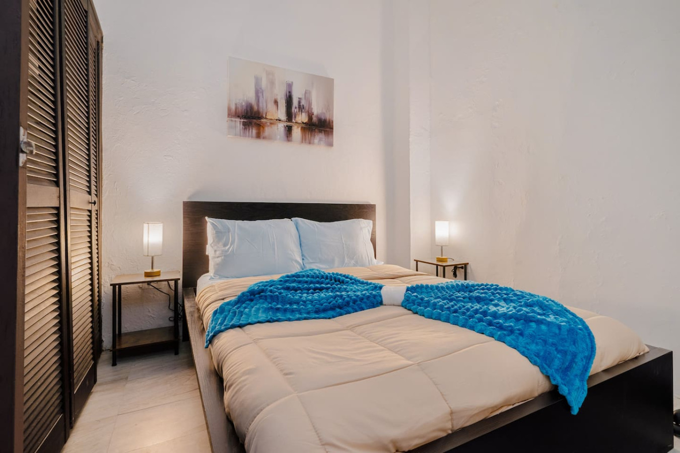 Bedroom with a blue comforter and a painting on the wall — Loft La Luz - Old San Juan, Old San Juan