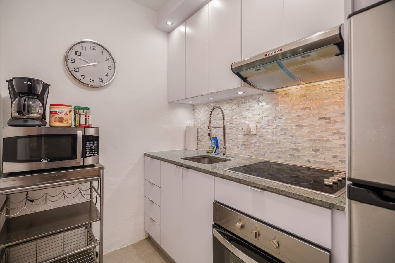Kitchen with a clock on the wall and a microwave on the counter — Punta Las Marias Studio - Short Walk to the Beach, Santurce
