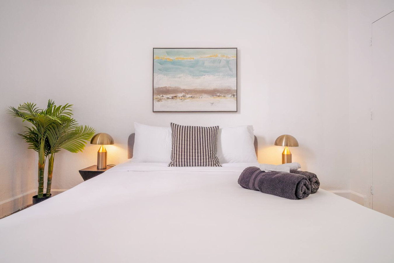 Bedroom with a white bedspread and a painting on the wall — Luz Collection No.2 – Casa Brisa | 3BR Retreat, Santurce