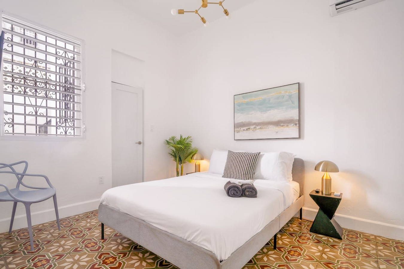 Bedroom with a bed, a potted plant, and a painting on the wall — Luz Collection No.2 – Casa Brisa | 3BR Retreat, Santurce