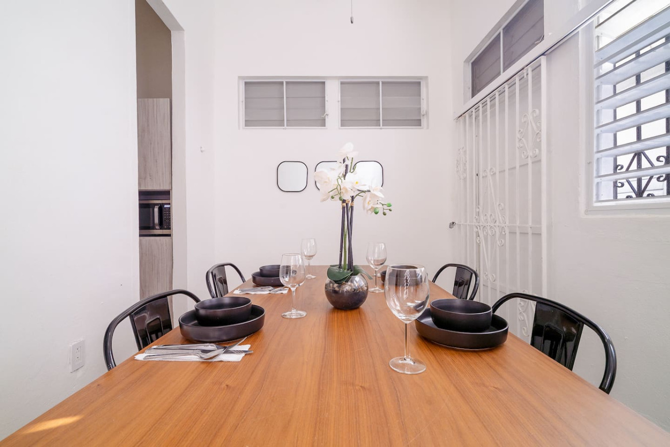 Wooden dining table with a vase of flowers on it — Luz Collection No.2 – Casa Brisa | 3BR Retreat, Santurce