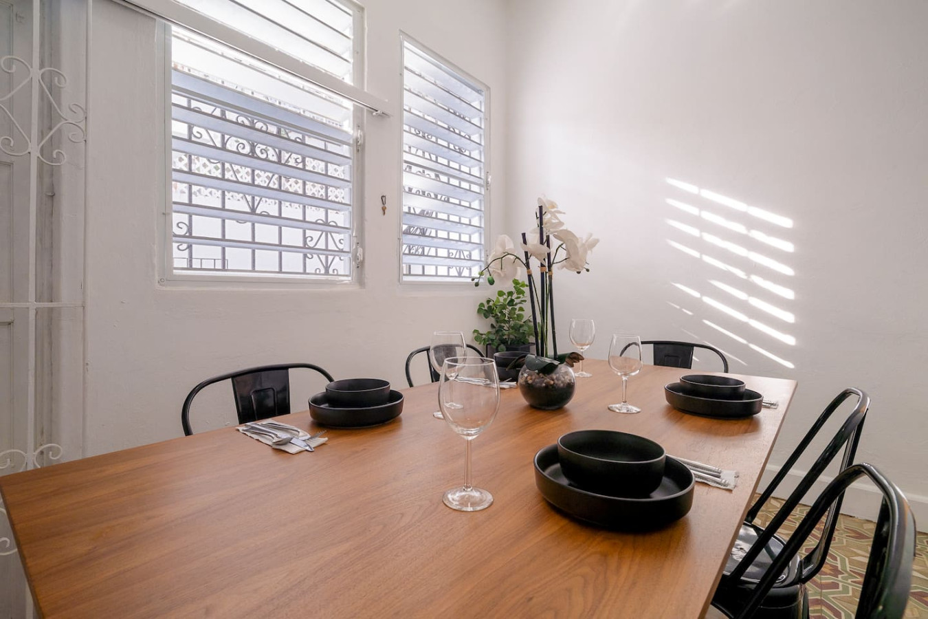 Dining area with a wooden table by louvered windows — Luz Collection No.2 – Casa Brisa | 3BR Retreat, Santurce