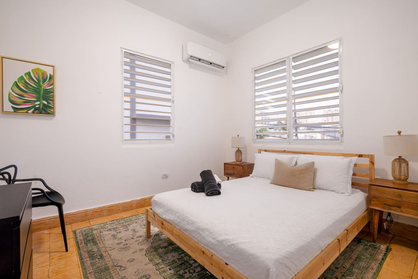Bedroom with a bed, nightstand, and a window with a view of the — Luz Collection No.3 – Casa Horizonte | 3BR Loft, Santurce