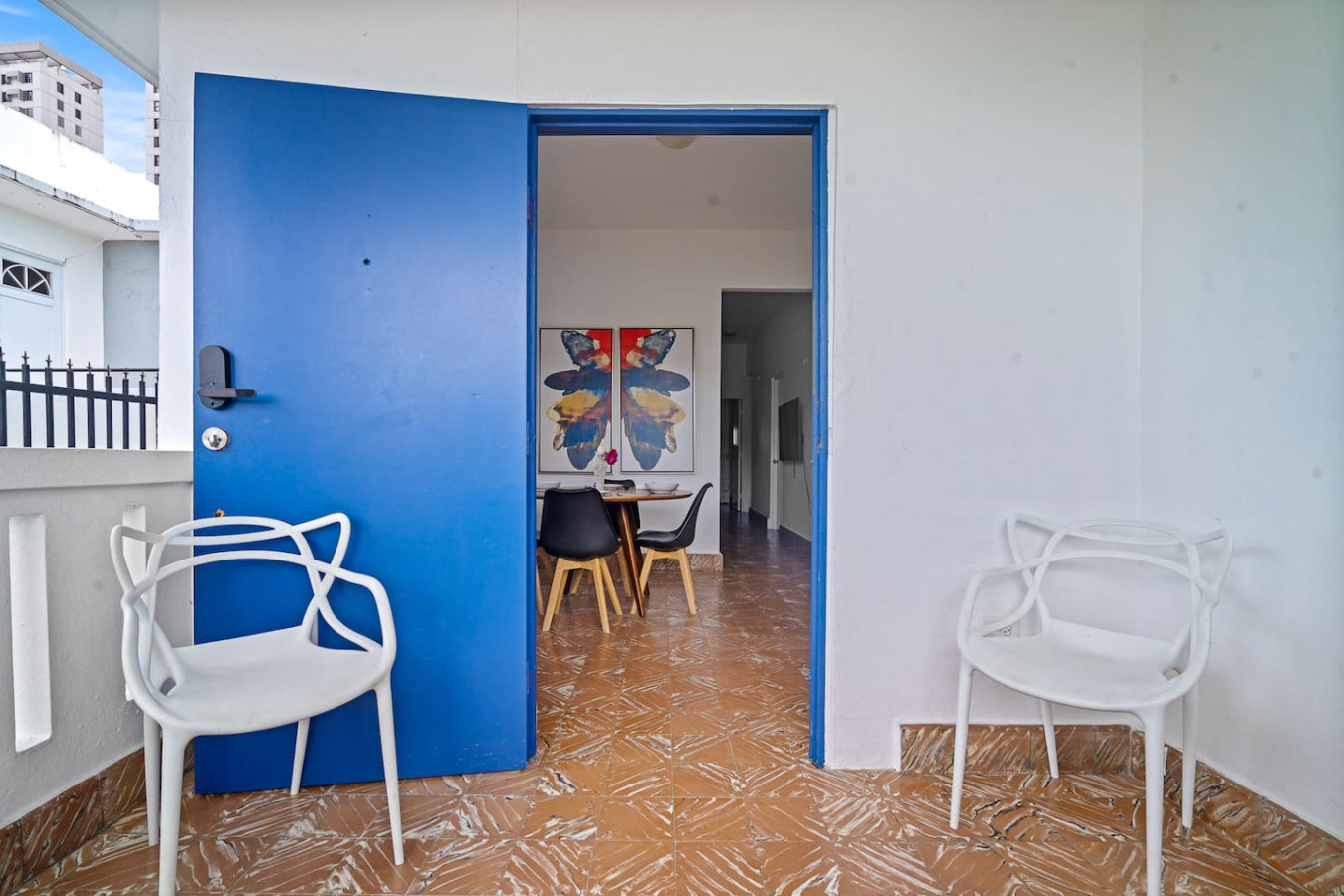 Balcony with two white seats beside the blue front door — Sunkiss in Puerto Rico San Juan 3 Bedroom, Santurce