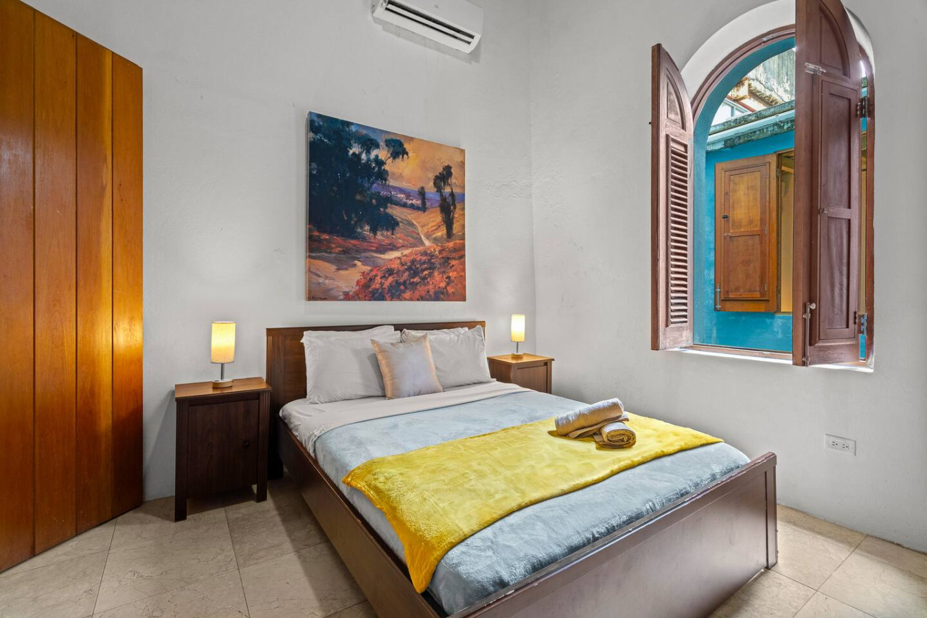 Bedroom with a yellow and blue bedspread and a painting on — Royal Imperial | Balcony Private | Old San Juan, Old San Juan