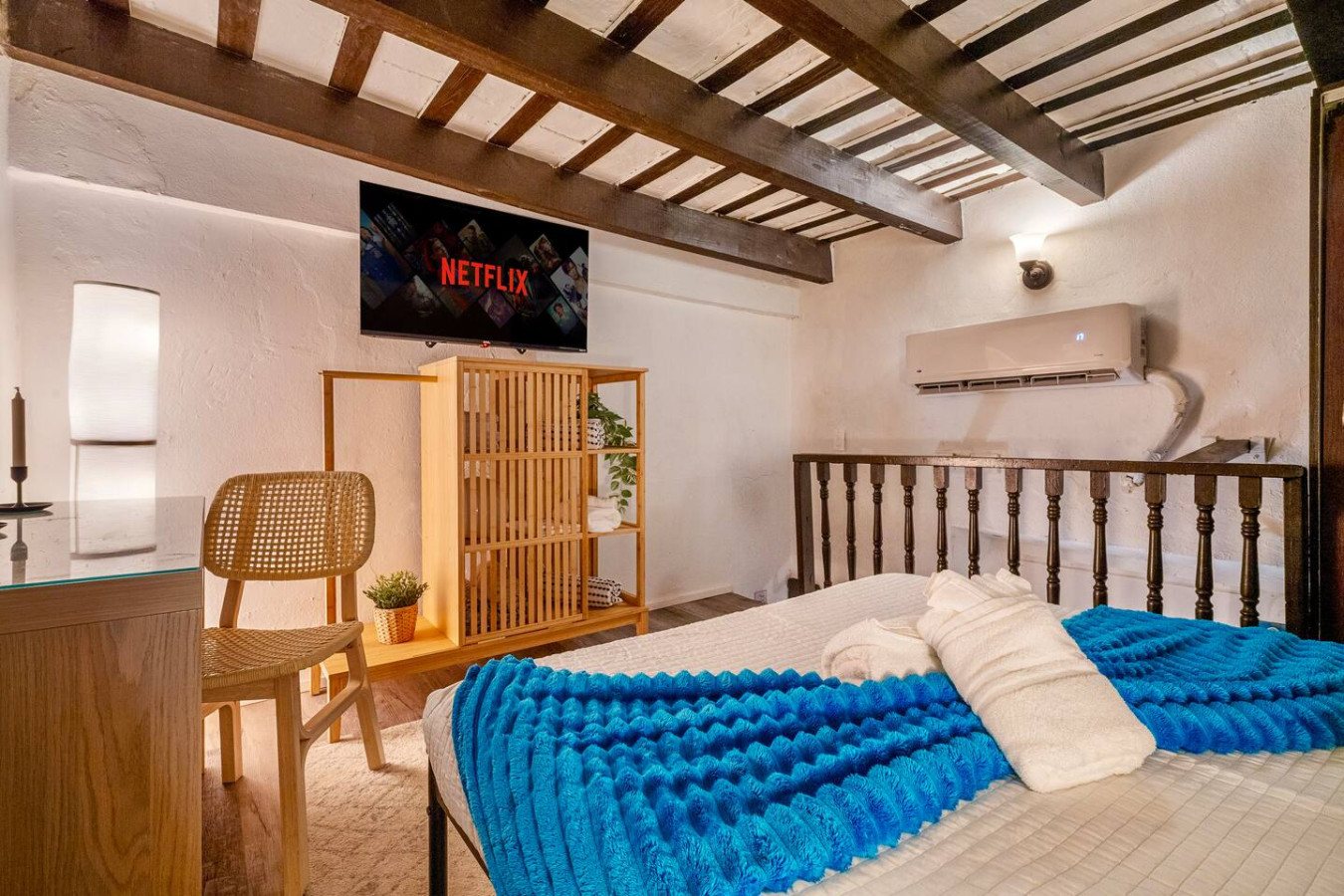 Bedroom with a blue comforter and a flat screen TV mounted on the wall — La Cueva Loft Rustic Colonial Romance, Old San Juan