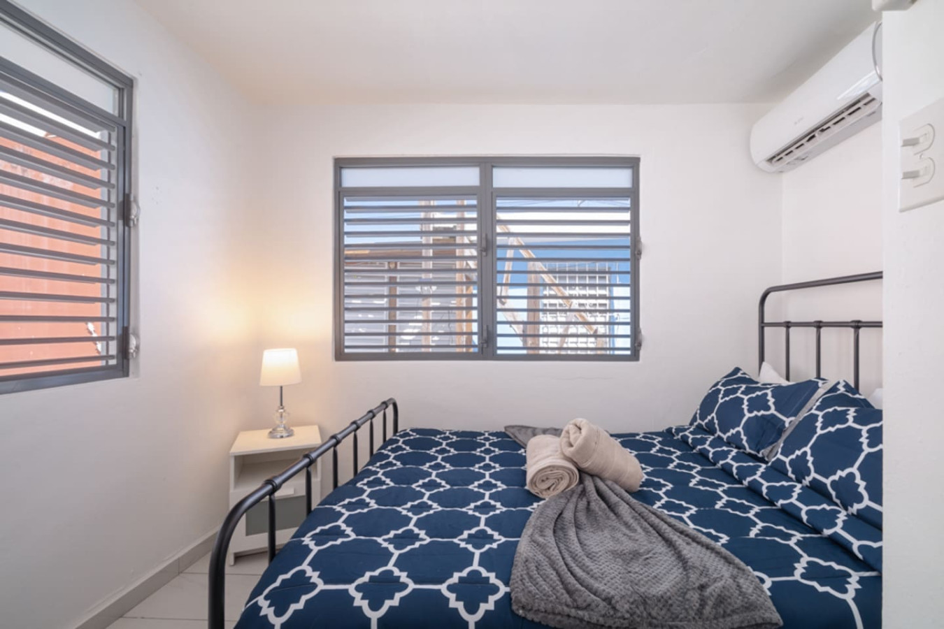 Bedroom with a bed, a lamp, and a window overlooking the city — Casa Juno Grand Modern - 3 Bedroom - Walk to Beach, Santurce