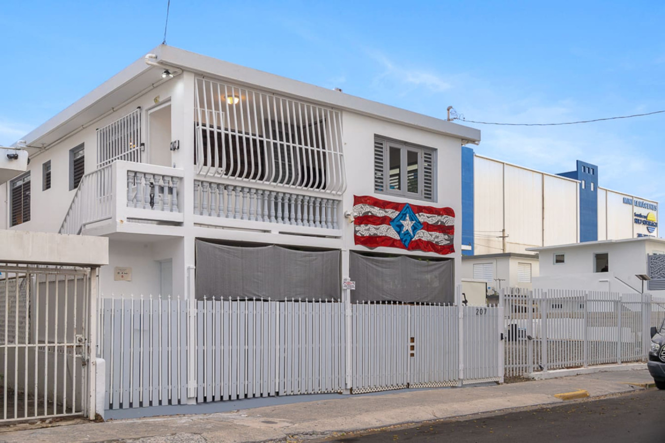 White house with a balcony and a flag on the front — Casa Juno I: Private Courtyard Studio, Santurce