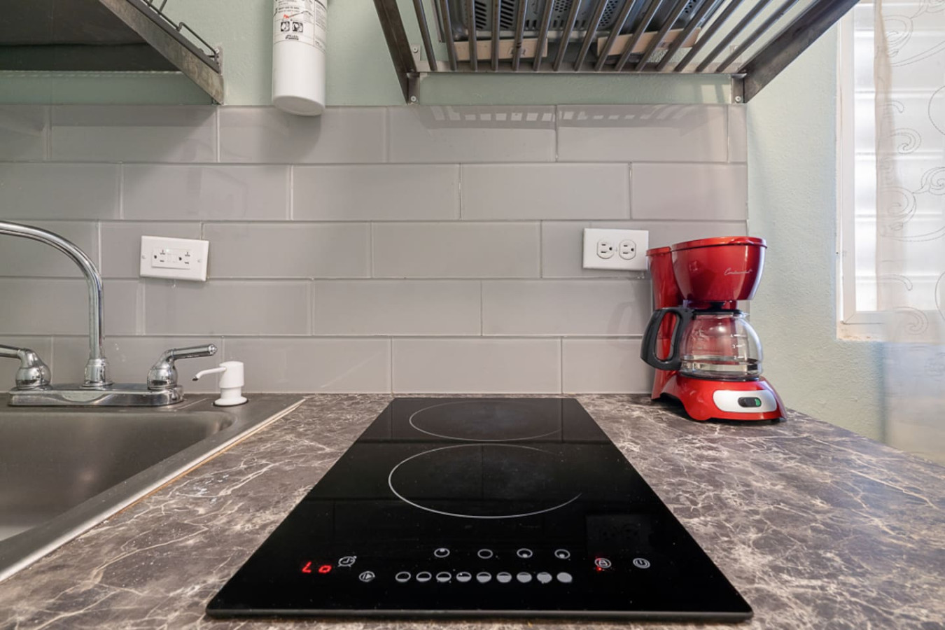 Kitchen counter with a two-burner glass cooktop — Casa Juno I: Private Courtyard Studio, Santurce