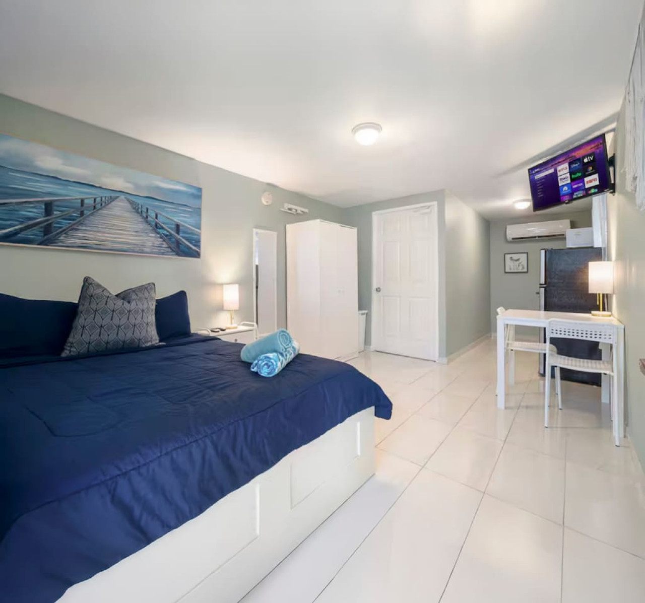 Bedroom with a blue bedspread and a painting on the wall (bedroom 5) — Casa Juno I: Private Courtyard Studio, Santurce