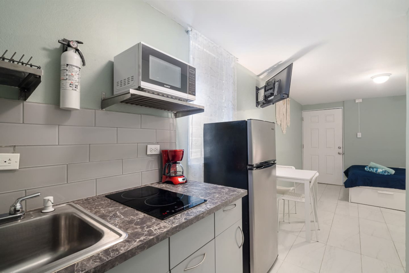 Kitchen with a stove top oven and a microwave above it — Casa Juno I: Private Courtyard Studio, Santurce