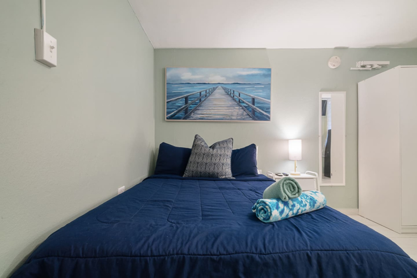 Bedroom with a blue bedspread and a painting on the wall (bedroom 4) — Casa Juno I: Private Courtyard Studio, Santurce